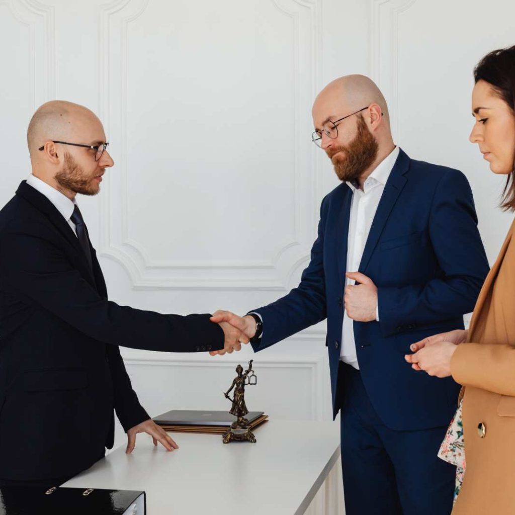 two men shaking hands over a desk