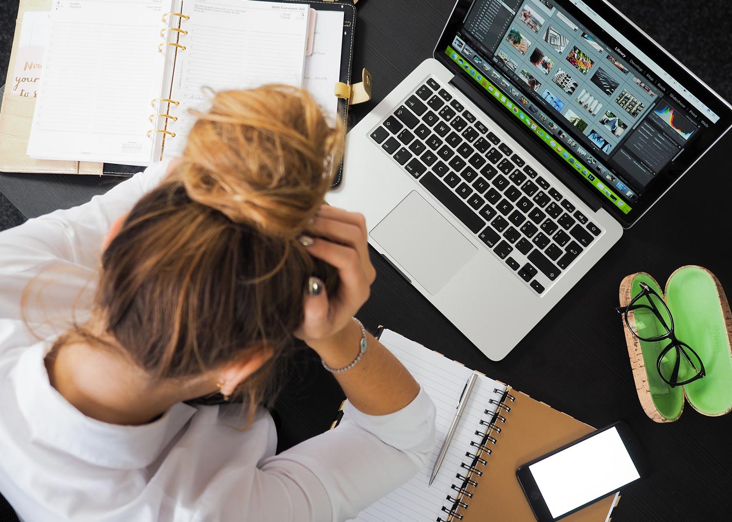 woman sitting in front of a macbook holding her head in her hands