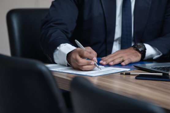 man sitting at a desk signing a document