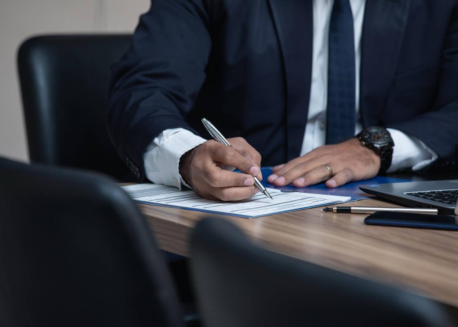 man sitting at a desk signing a document