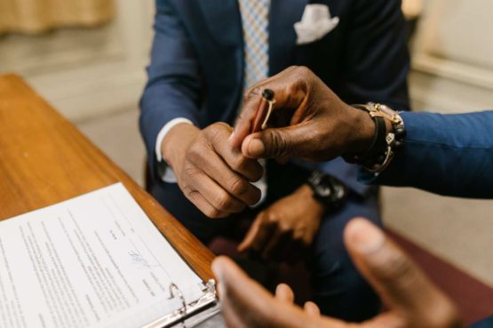 lawyer handing client a pen to sign a contract