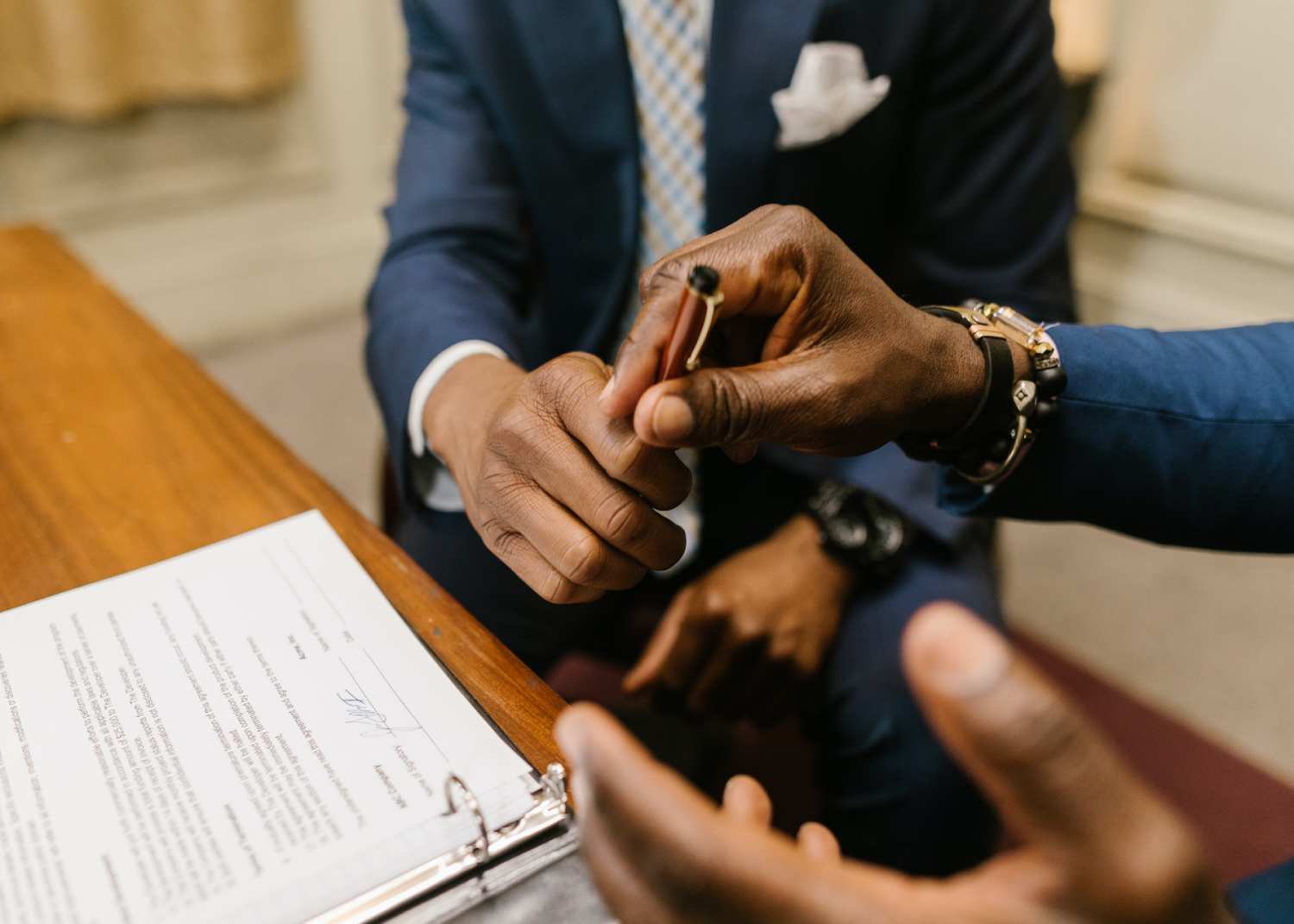 lawyer handing client a pen to sign a contract