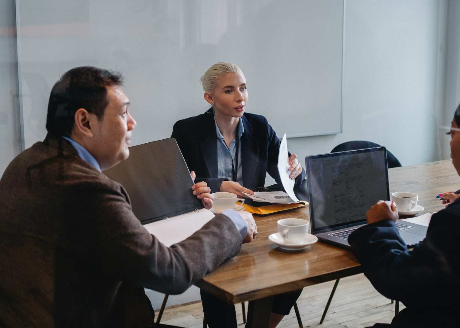 three people a round a table in a meeting