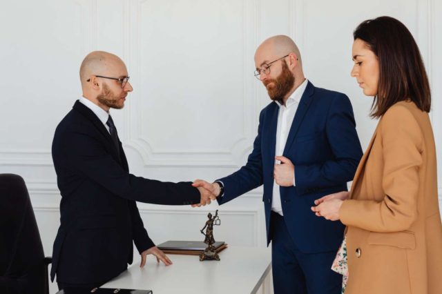 two men shaking hands over a desk