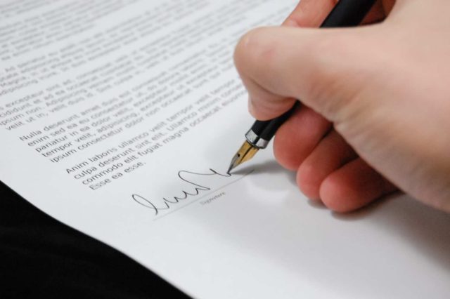 close up of a hand signing a document